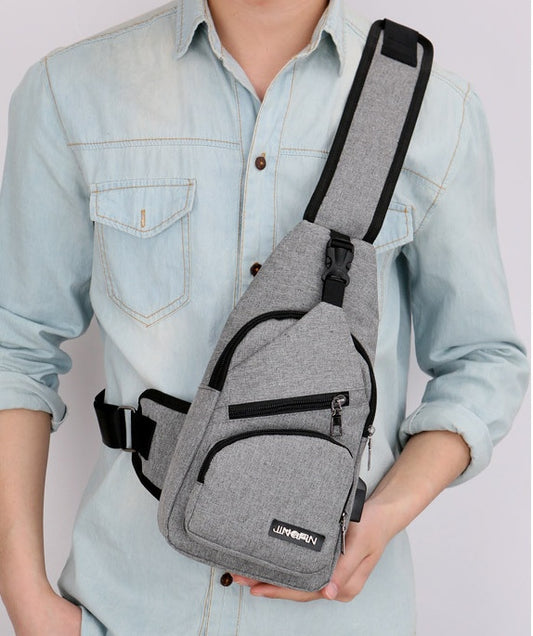 Person holding a gray sling bag with black accents on a plain background