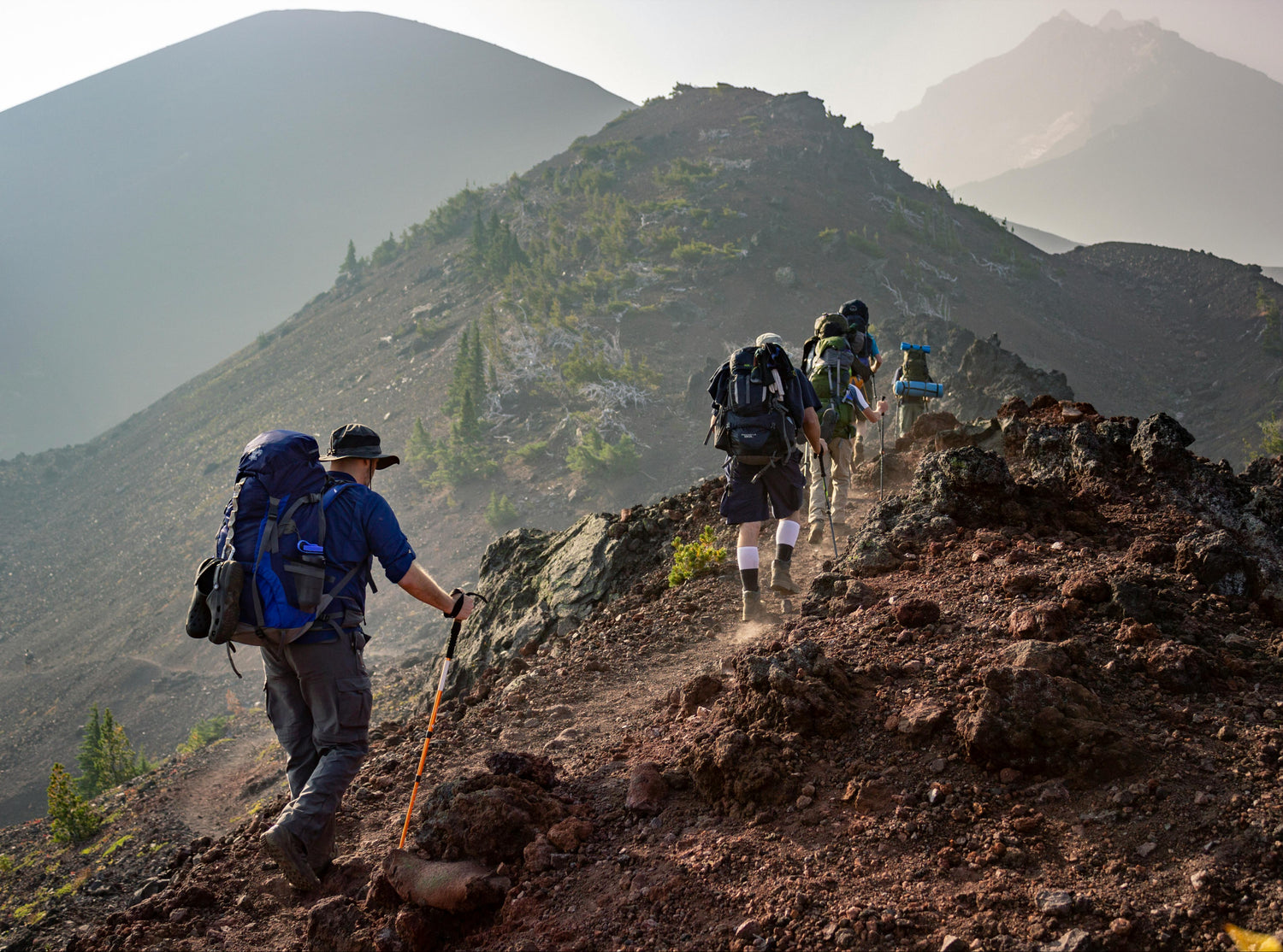 Group of hikers with backpacks climbing a mountain trail.